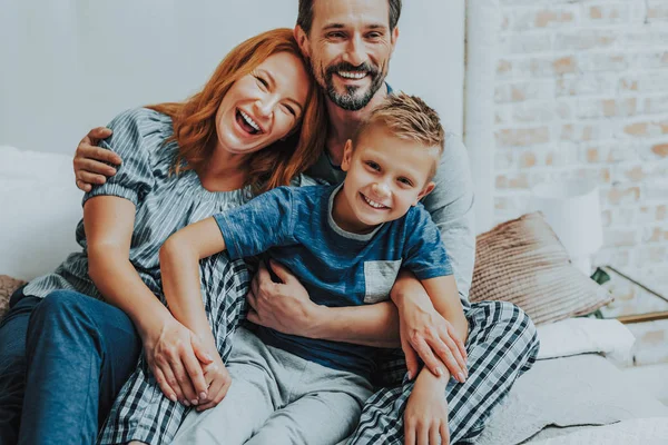 Gelukkige jongen zittend met ouders op bed — Stockfoto