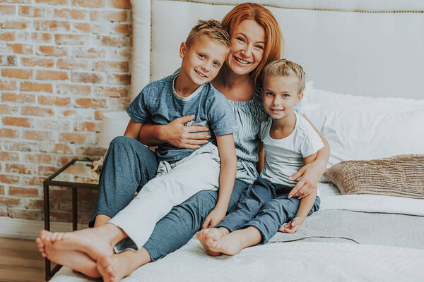 Happy mom and two kids relaxing in bed