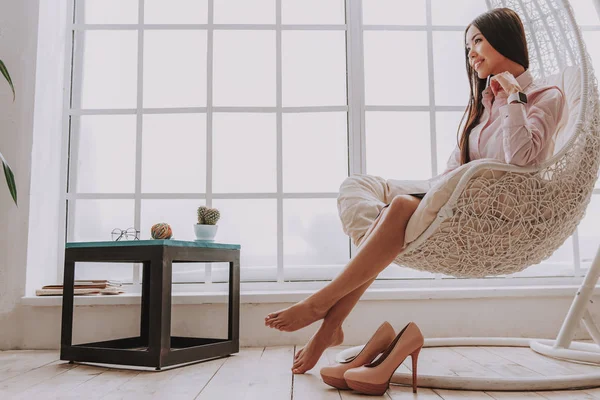 Sorrindo jovem mulher descansando em cadeira aconchegante — Fotografia de Stock