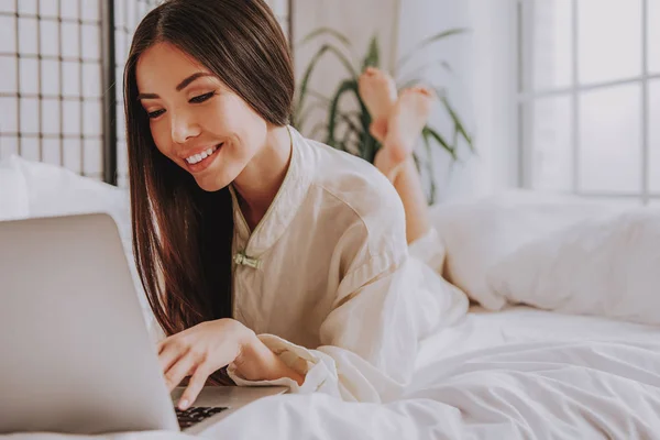 Jovem feliz digitando no teclado do computador no quarto — Fotografia de Stock