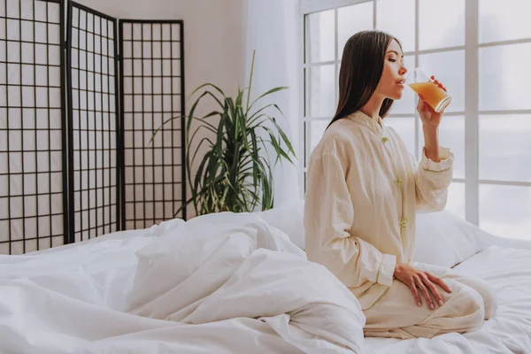 Ήρεμη Ασιατική γυναίκα πίνοντας νόστιμο χυμό στο υπνοδωμάτιο — Φωτογραφία Αρχείου