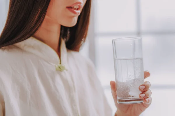 Young girl taking glass of water with medicine near window — Stock Photo, Image