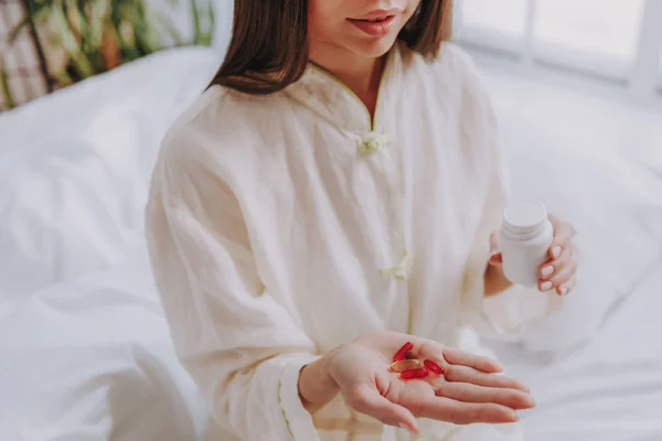 Giovane ragazza che tiene le capsule e un bicchiere d'acqua tra le mani — Foto Stock