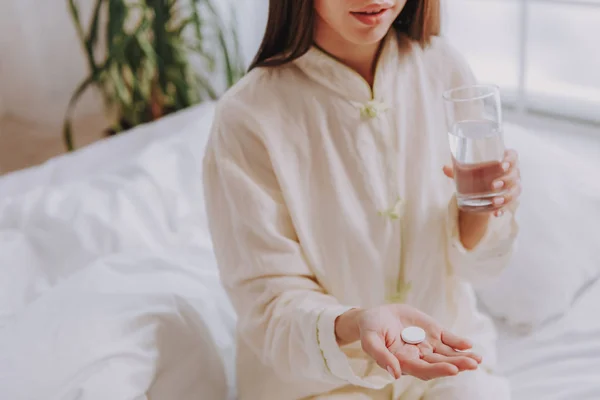 Joven chica mantener píldora y vaso de agua en el apartamento —  Fotos de Stock