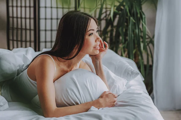 Hermosa joven mujer soñando en un acogedor dormitorio — Foto de Stock