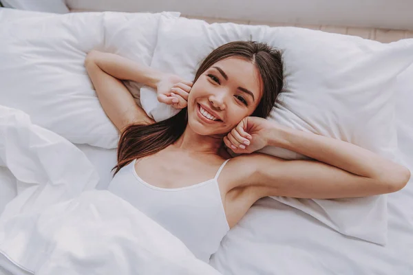 Encantadora chica asiática después del sueño acostada en una cama suave — Foto de Stock