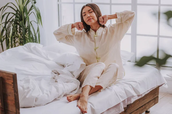 stock image Pretty serene woman sitting on soft bed at home