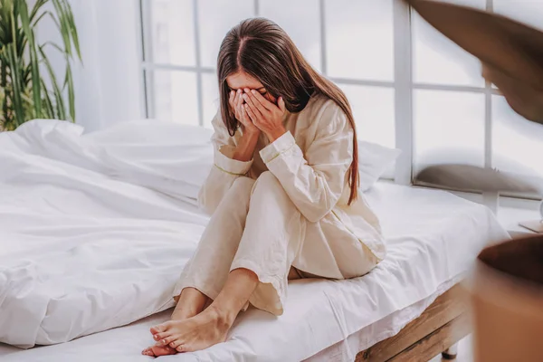 Mujer joven sentada en la cama en un acogedor apartamento —  Fotos de Stock