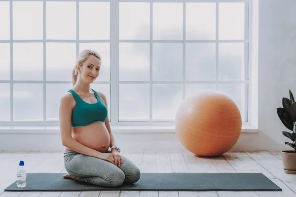 Happy expectant woman resting after yoga in cozy living room