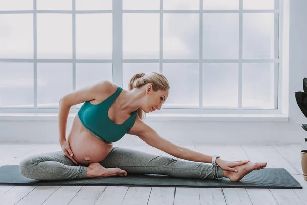 Beautiful future mother is stretching at home — Stock Photo, Image