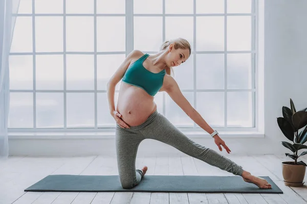 Pretty expectant female in workout clothes doing yoga — Stock Photo, Image