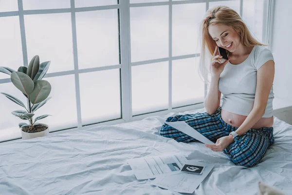 Aranyos várandós nő nézett ultrahangos fénykép ágyon pizsama — Stock Fotó