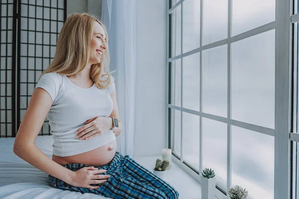 Ridere donna in attesa seduto sul divano a casa — Foto Stock