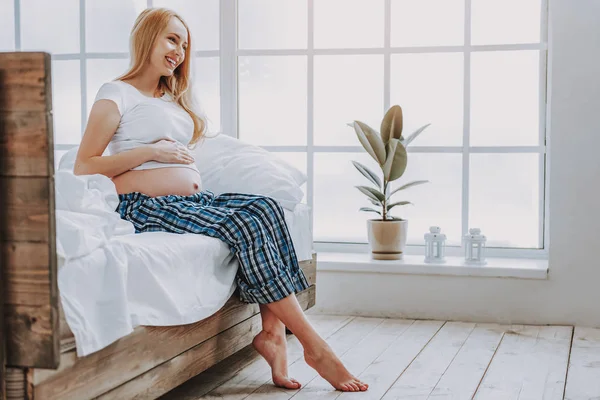Feliz embarazada en pijama sentada en la cama —  Fotos de Stock