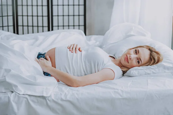 Симпатична майбутня жінка лежить на ліжку вдома — стокове фото