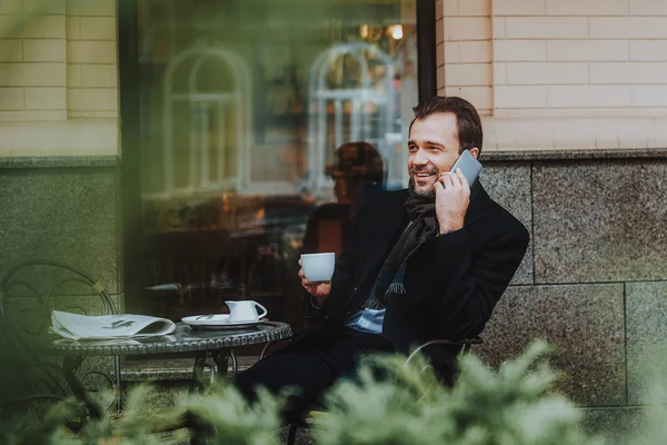 陽気な人は、コーヒーのカップと電話で話しています。 — ストック写真