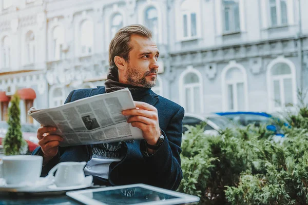 Zrelaksowany człowiek jest czytanie gazety w kawiarni — Zdjęcie stockowe