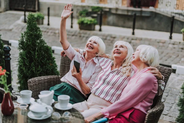 Drei lächelnde Damen sitzen und schauen auf — Stockfoto