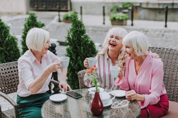 Tres mujeres con estilo tienen conversación en la cafetería de la calle —  Fotos de Stock