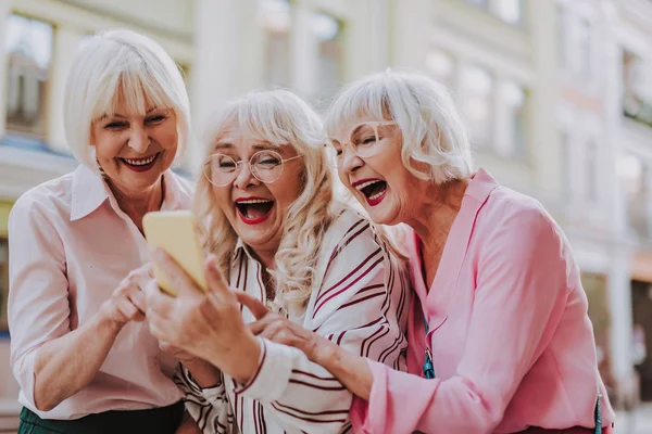 Tres ancianas mirando el teléfono y riendo — Foto de Stock