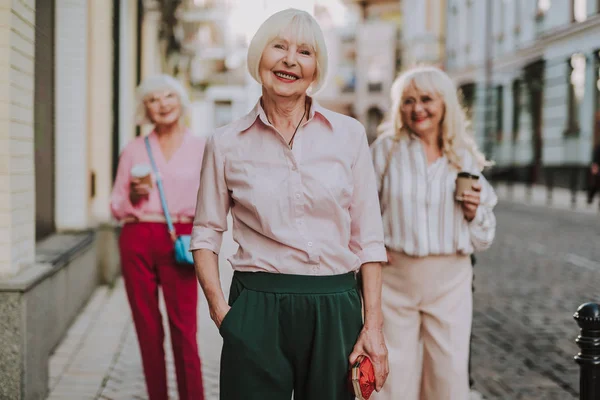 Hermosa anciana de pie con sus amigos — Foto de Stock