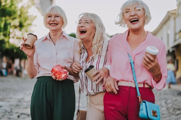 Tres sonrientes damas caminando por la ciudad — Foto de Stock