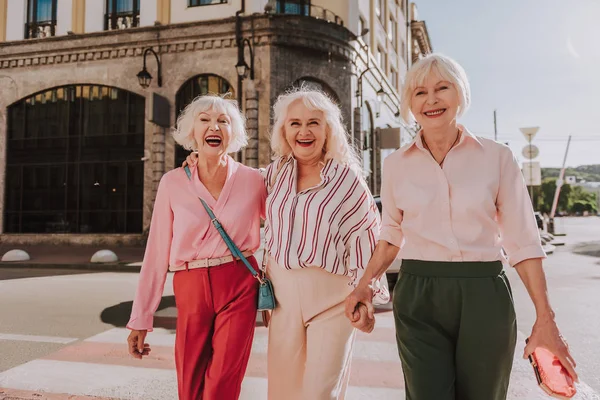 Смеющиеся пожилые дамы держатся за руки на открытом воздухе — стоковое фото