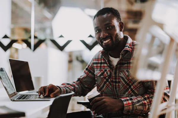 Taille van positieve bebaarde Afro-Amerikaanse man zitten met laptop — Stockfoto