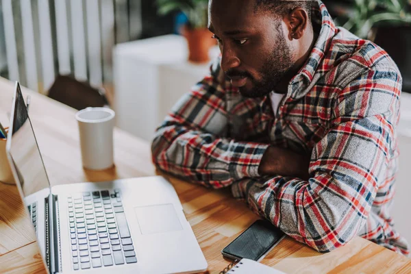 Bearded young man looking at the screen of his laptop