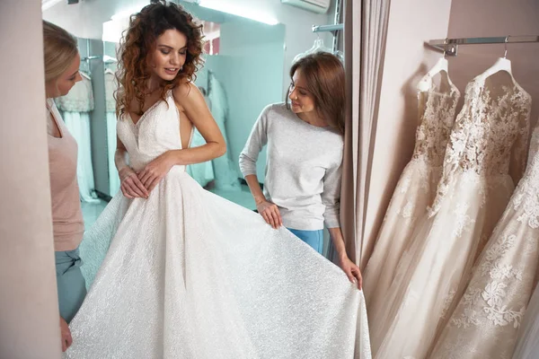 Jovem noiva experimentando vestido no salão de casamento — Fotografia de Stock