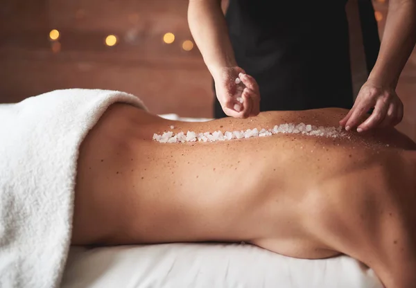 Terapeuta feminina faz massagem de sal para jovem — Fotografia de Stock
