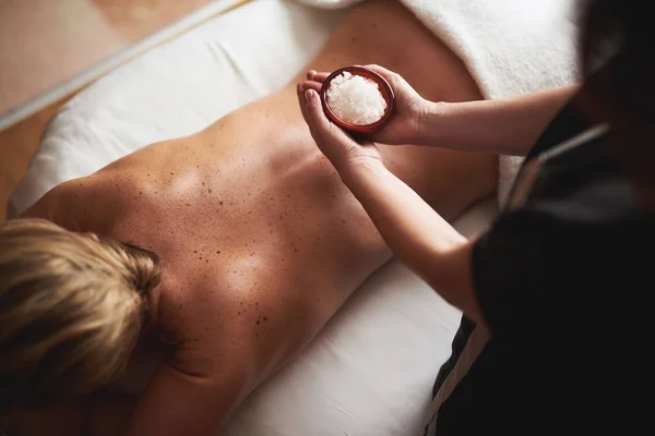 Övre vinkeln av massageterapeut med skål salt — Stockfoto