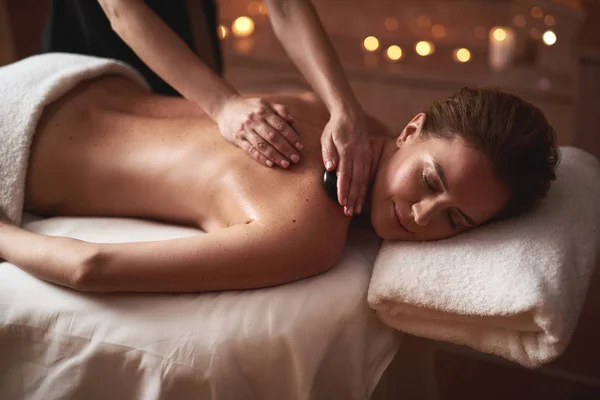 Young lady having massage with warm stones