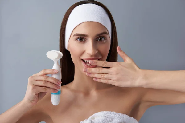 Emocionado chica feliz sosteniendo cepillo de limpieza de poros y cubriendo la boca con la mano — Foto de Stock