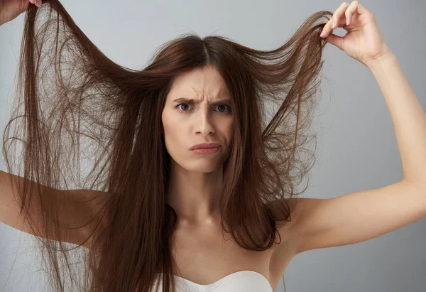 Displeased young lady in white bra demonstrating her damaged hair — Stock Photo, Image