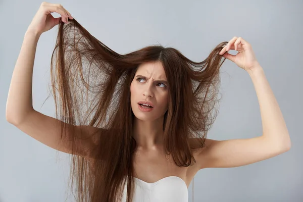 Descontente jovem senhora em sutiã branco olhando para seu cabelo danificado — Fotografia de Stock