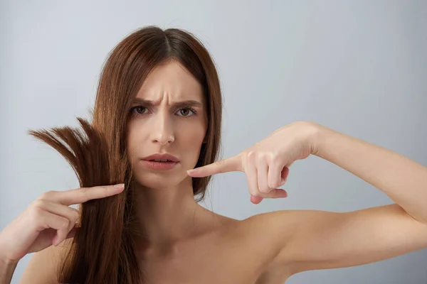 Meisje met naakte schouders tonen haar beschadigde haren ontevreden — Stockfoto