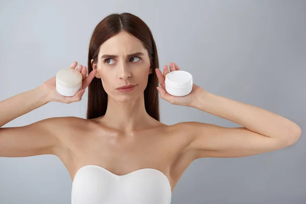 Menina bonita em sutiã branco segurando produtos cosméticos — Fotografia de Stock