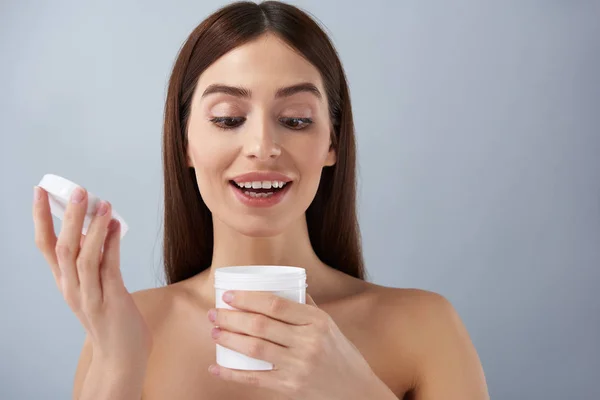 Jovencita alegre abriendo frasco blanco de crema cosmética — Foto de Stock