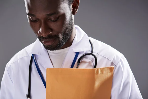 Ernsthafter afroamerikanischer Arzt vor grauem Hintergrund — Stockfoto