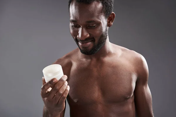 Vrolijke knappe afro Amerika man met een crème pot — Stockfoto