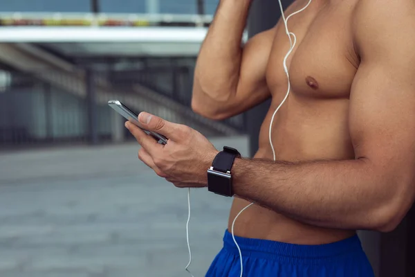 Manliga arm att hålla modern mobil med hörlurar — Stockfoto