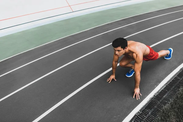 Centrado hombre de pecho desnudo preparándose para correr al aire libre — Foto de Stock