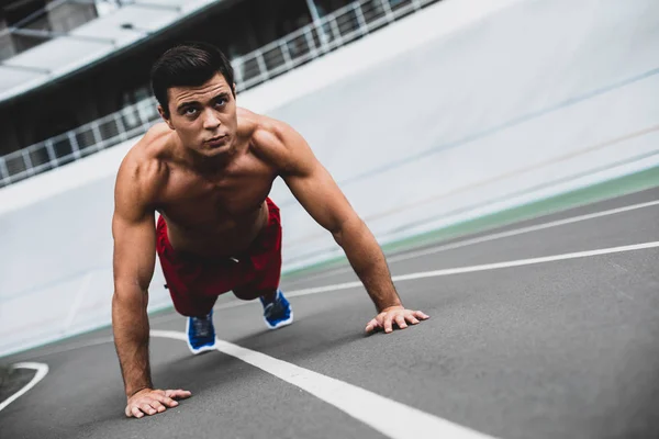 Hombre concentrado con cuerpo atractivo haciendo ejercicio — Foto de Stock