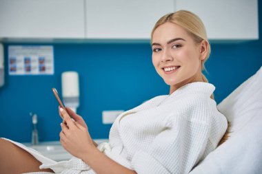 Güzellik salonunda cep telefonu kullanarak çekici genç kadın