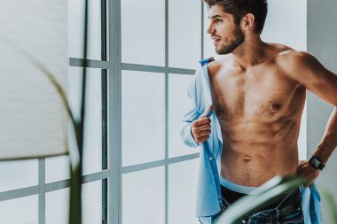 Üzerinde çalışmaya gitmek için gömleğini giyen genç adam