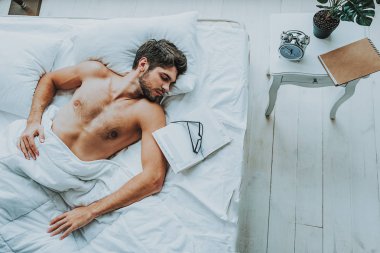 Yakışıklı erkek yatakta okuduktan sonra uyku