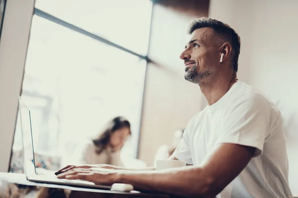 Homme rêveur utilisant netbook, levant les yeux et souriant — Photo