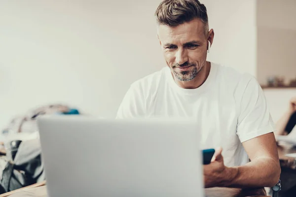 Homme souriant tenant le téléphone et regardant sur netbook — Photo