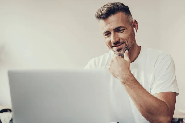 Homem atraente olhando para monitor de laptop e fazendo sorriso — Fotografia de Stock